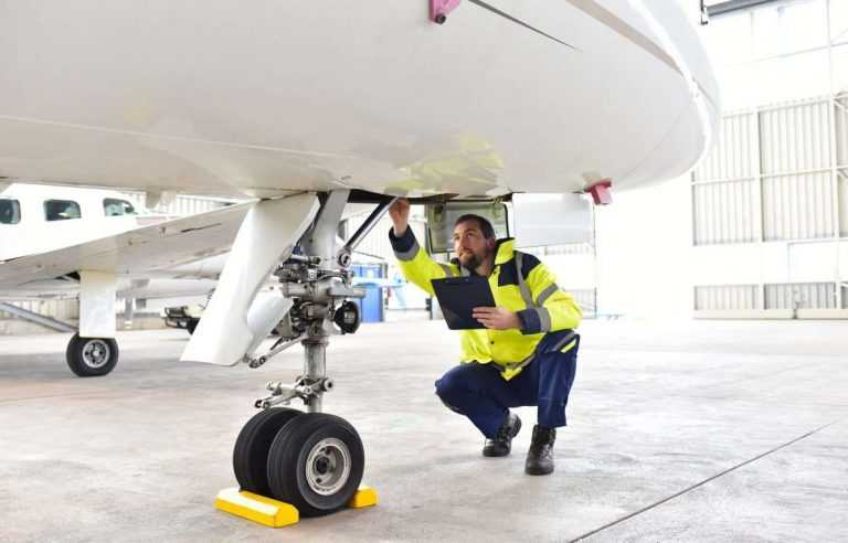 Man inspecting front wheel of airplane