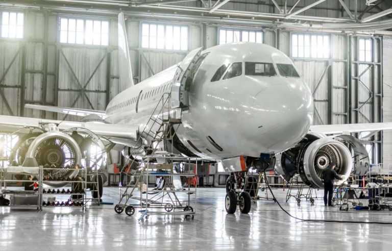 People servicing large plane with turbine engines opened