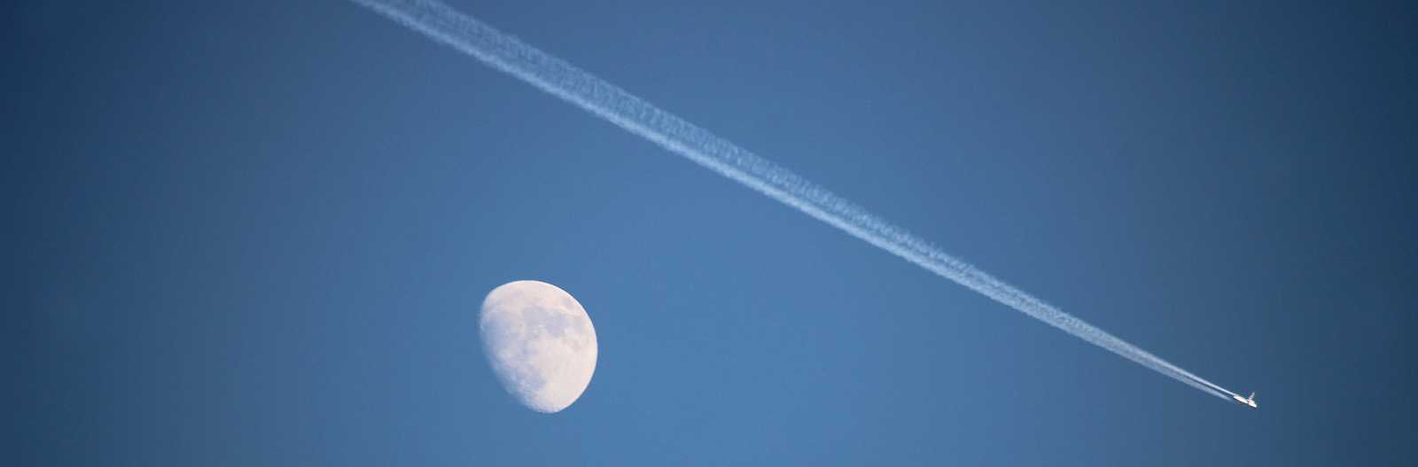 contrails with a moon in the background