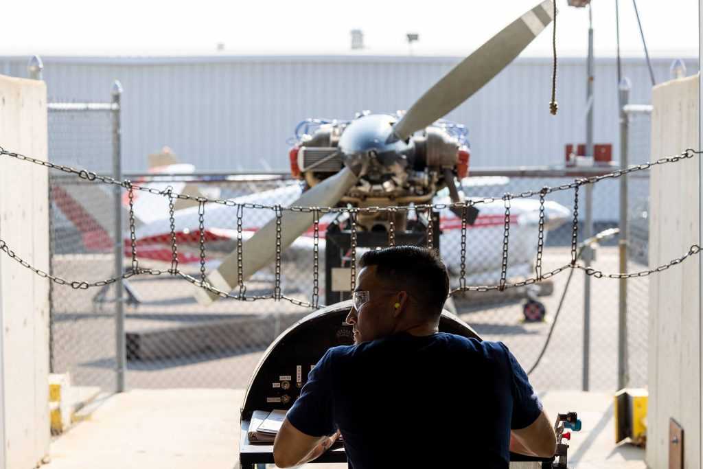 tech student in front of prop plane engine